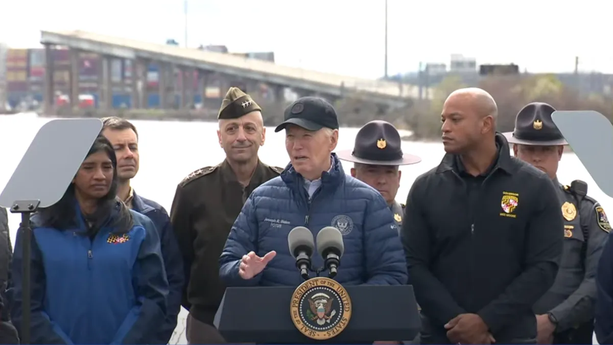 President Joe Biden stands at a microphone with the wreckage of Baltimore's Francis Scott Key Bridge behind him.