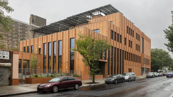 The exterior of a building on a rainy day. The blocky structure sits at the corner of a street.