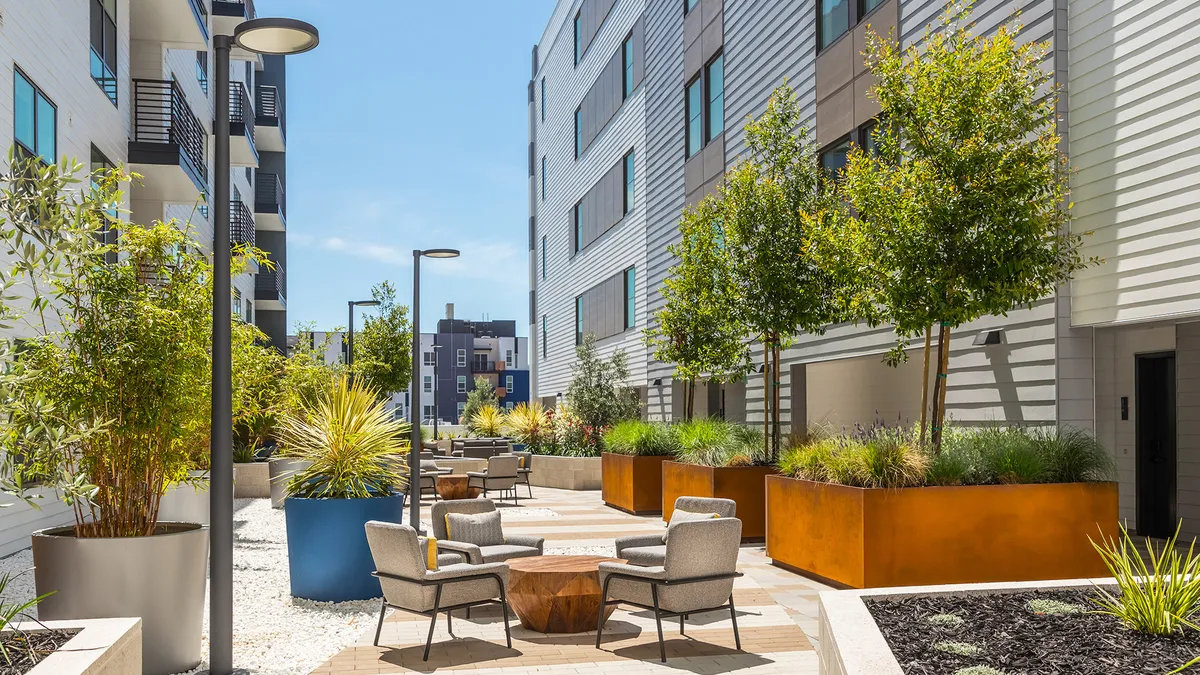 Tress and chairs between two tan-colored apartment buildings