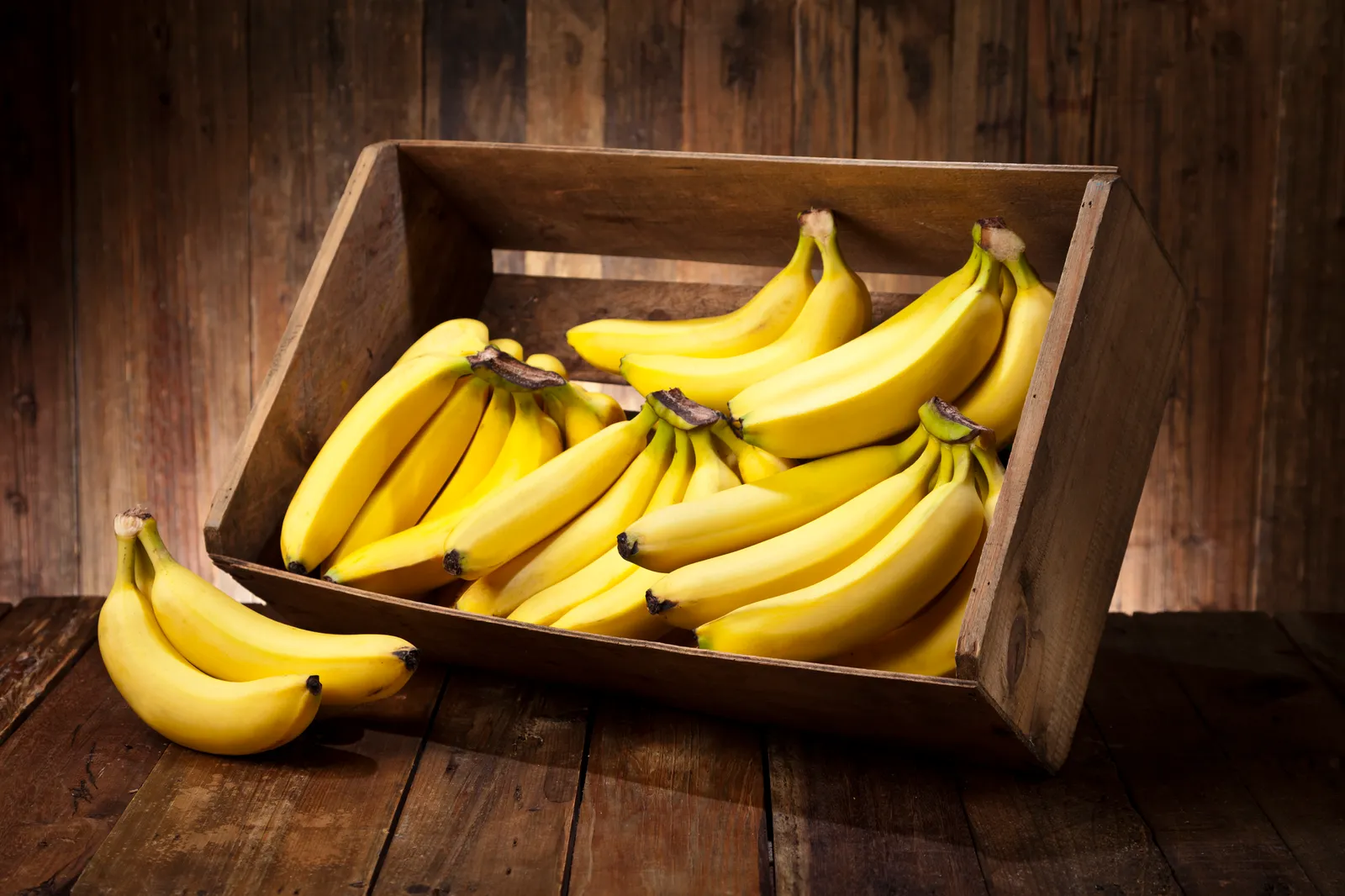 A photo of bananas in a wooden crate on a table.