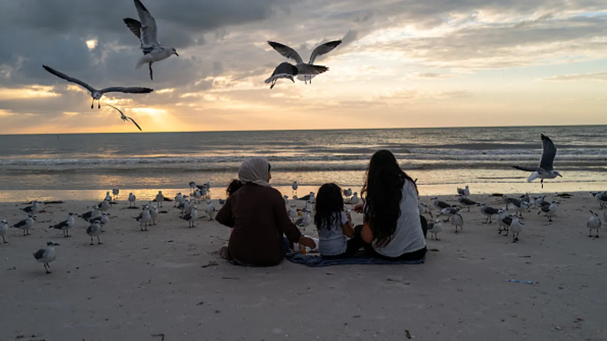 Three people sitting on a beach