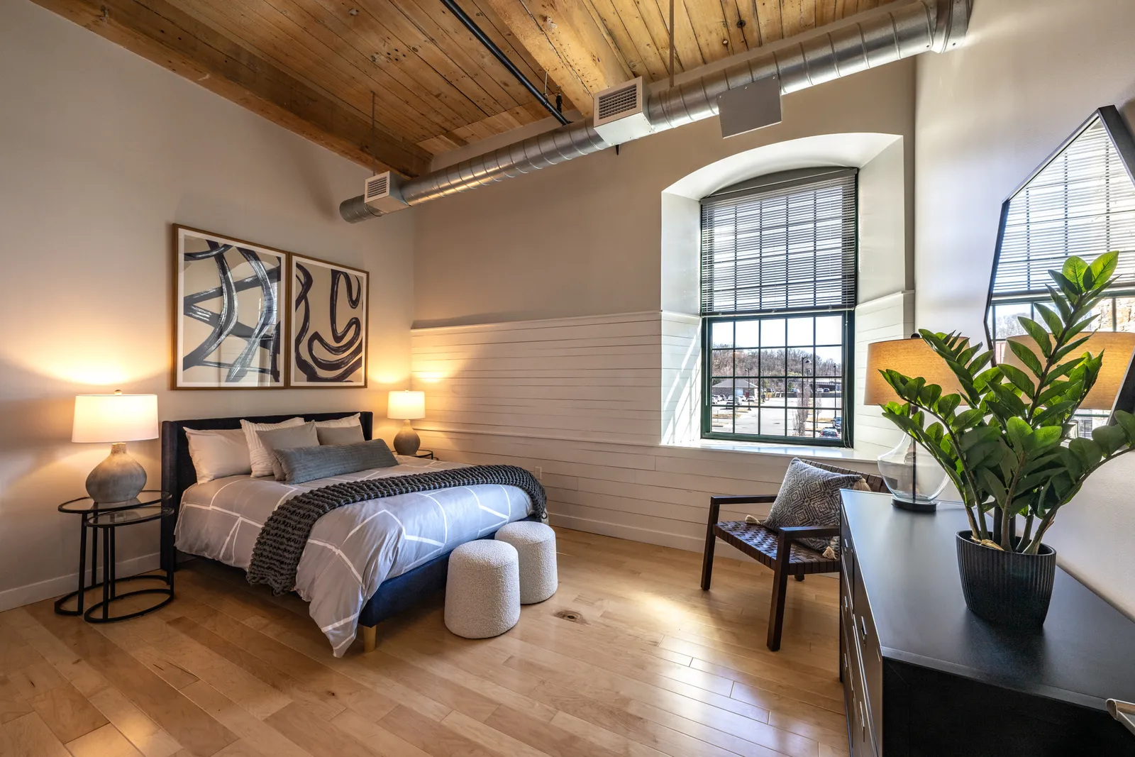 A bedroom with brick walls and an exposed wooden ceiling.