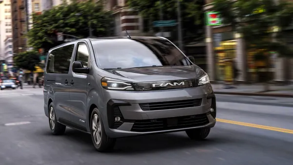 A gray Ram ProMaster City van moves along a congested American street.