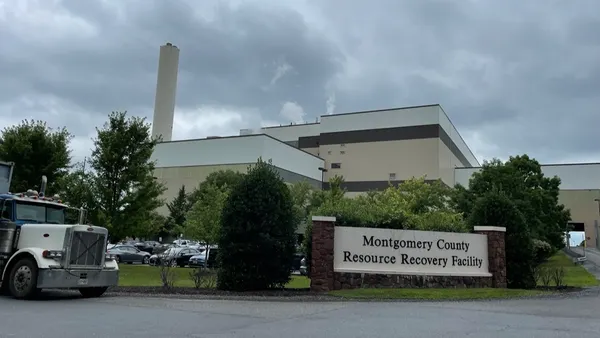 Exterior of a large industrial building with a smokestack and semi truck parked out front. A sign at the entrance reads "Montgomery County Resource Recovery Facility."