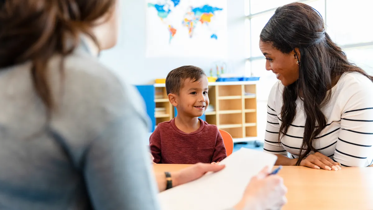 A child psychologist talks with a boy and his mom during a play therapy appointment.