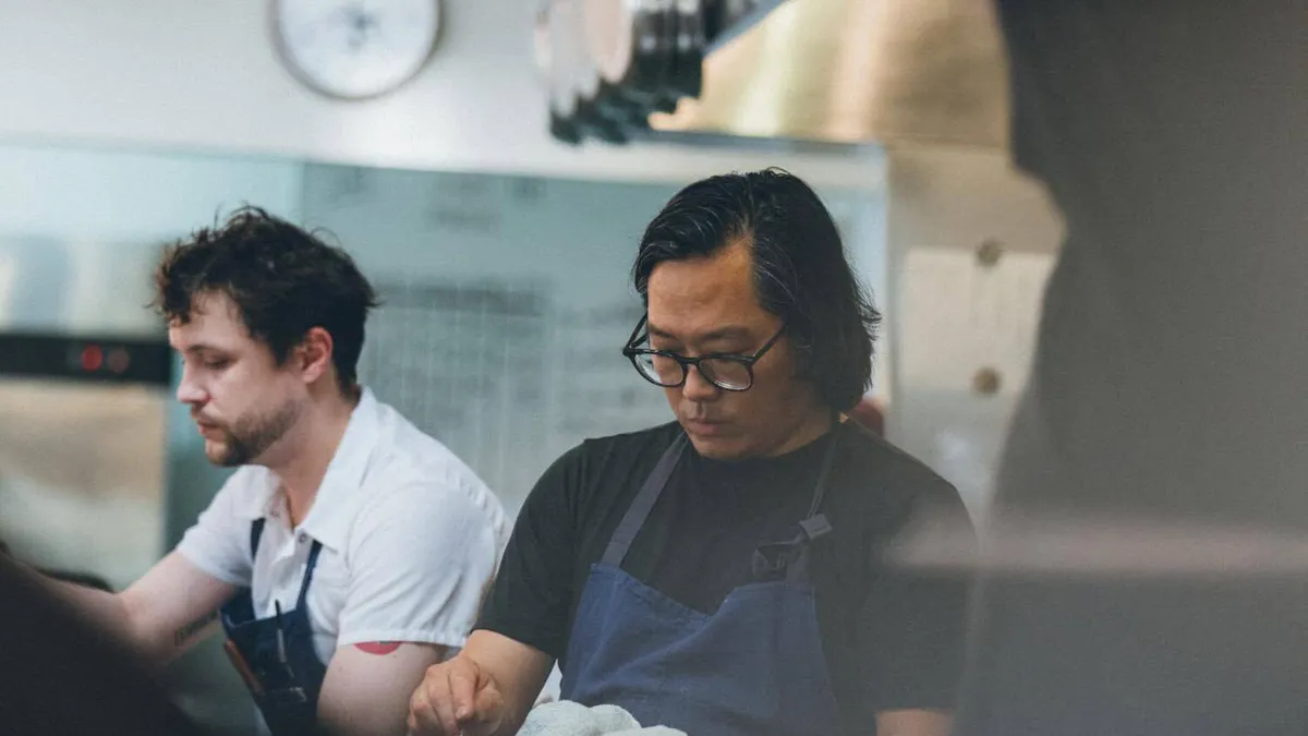 Two cooks sitting in their restaurant kitchen.