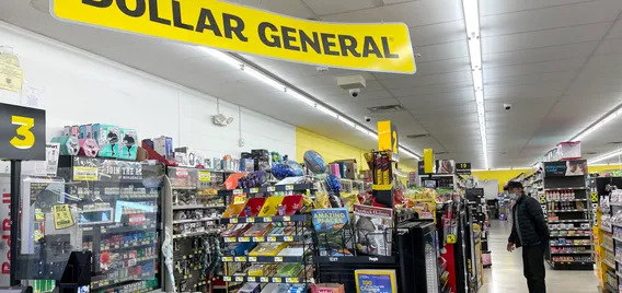 Interior of a store with a yellow "Dollar General" sign hanging from the ceiling.