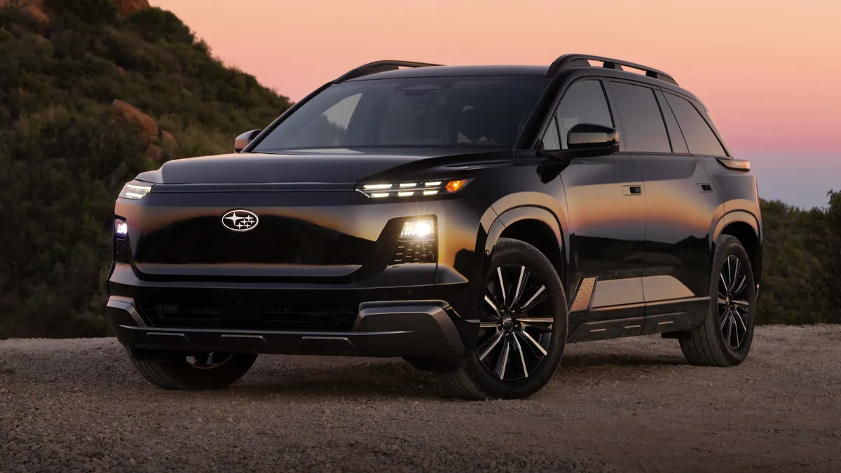 A black 2027 Subaru Getaway electric SUV parked outdoors with an orange sky in the background.