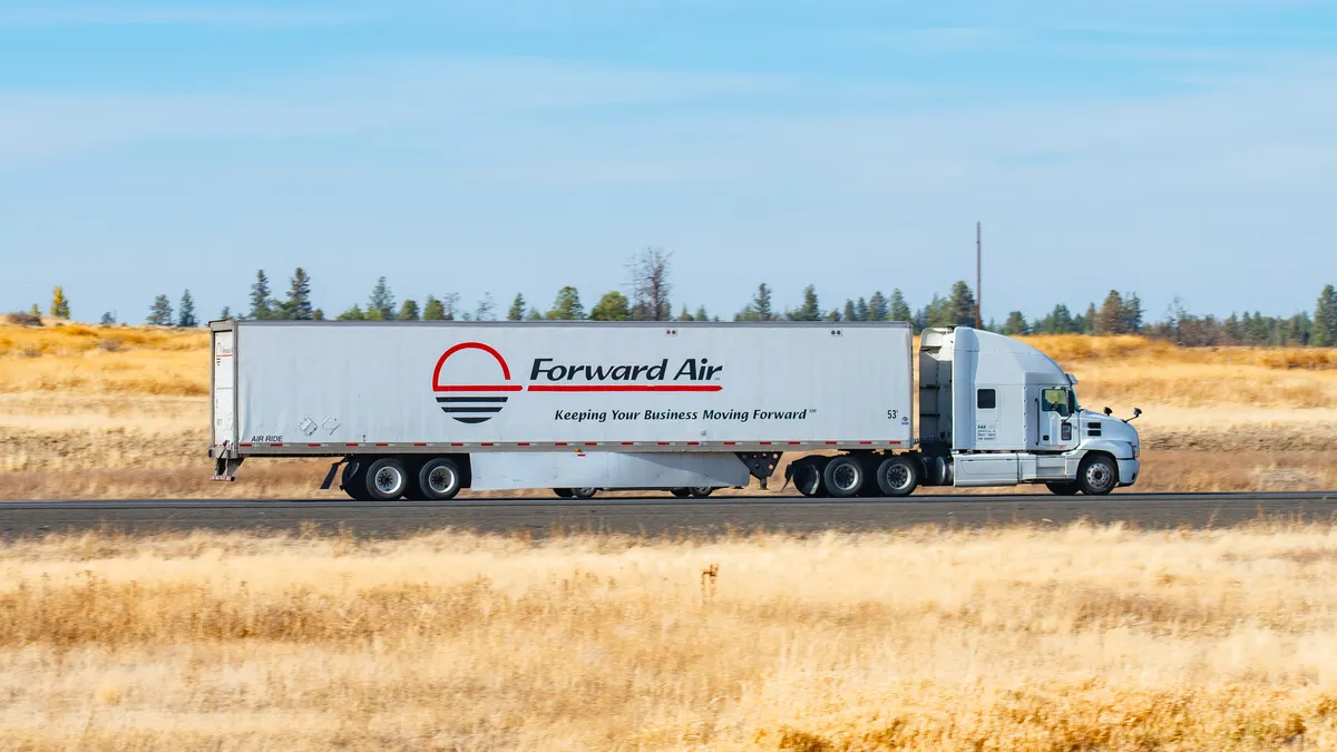 A Forward Air semi-truck driving on a rural section of Interstate 90 in eastern Washington state with some trees in the background.