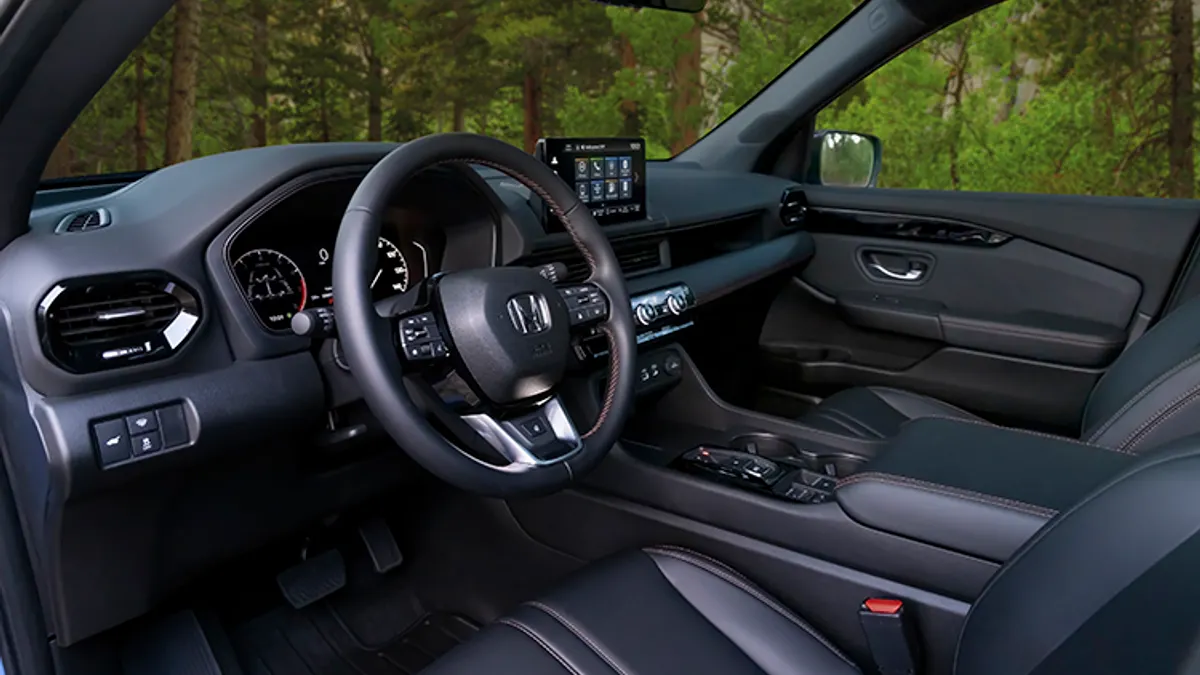 The driver side of a 2023 Honda Pilot SUV showing the steering wheel and dashboard.