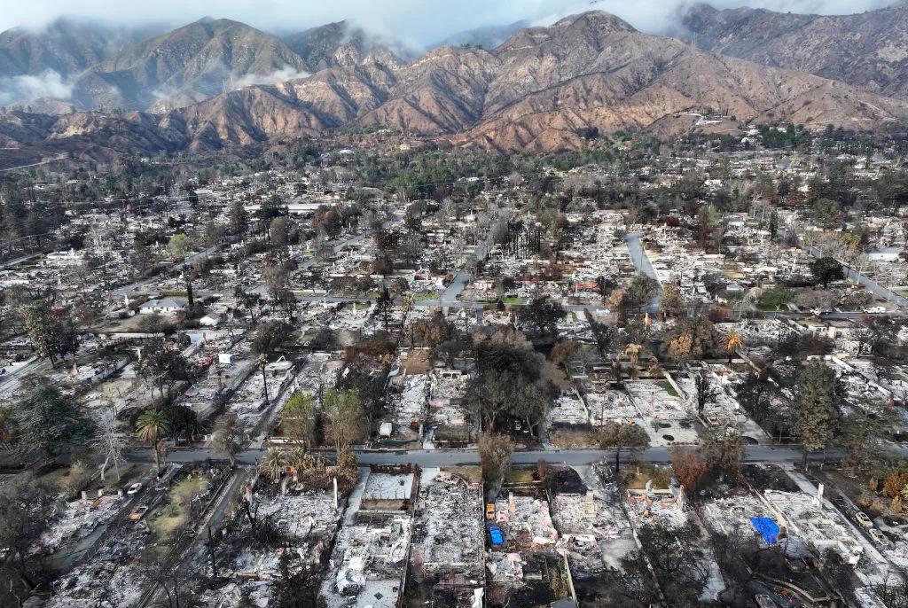 An aerial view of a burned-out neighborhood with mountains in the background.