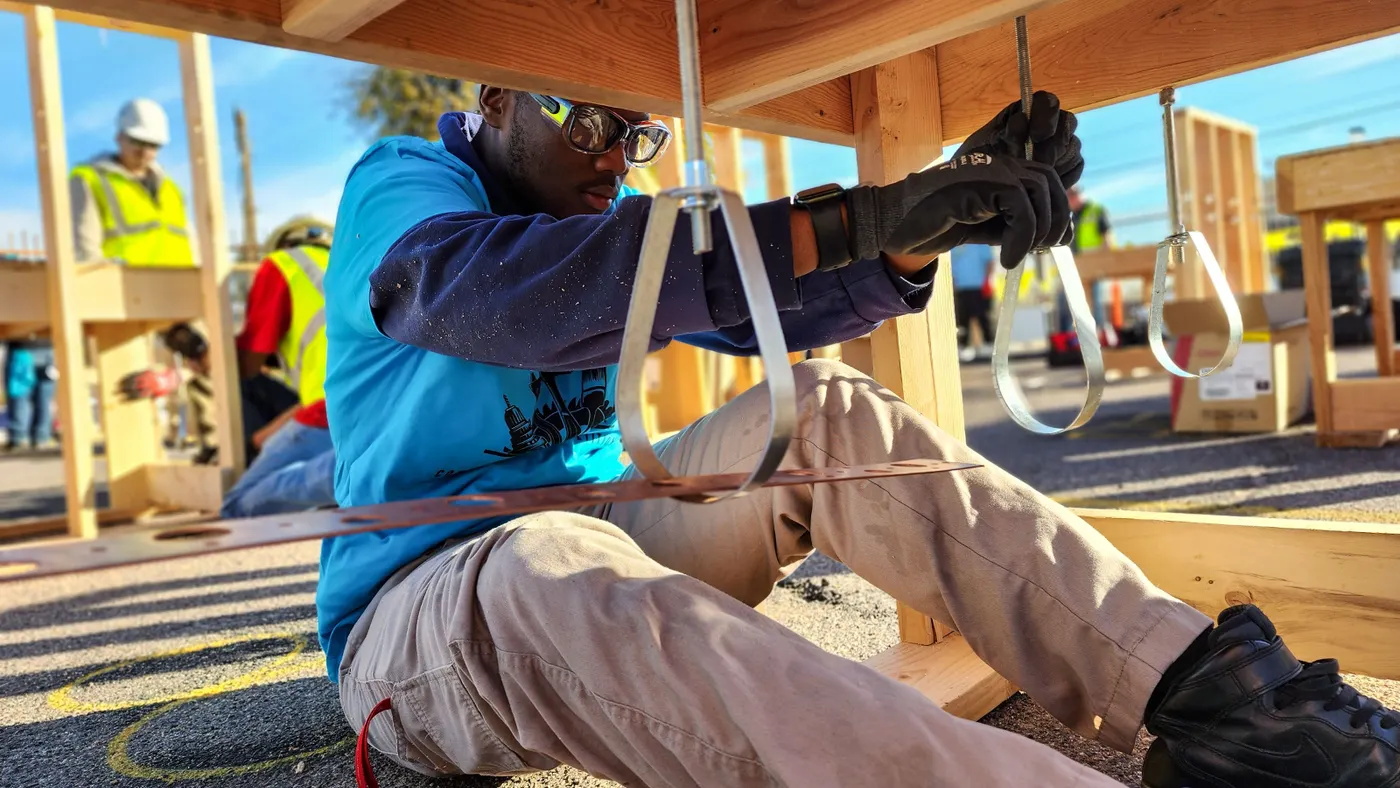 A construction worker builds a small structure.