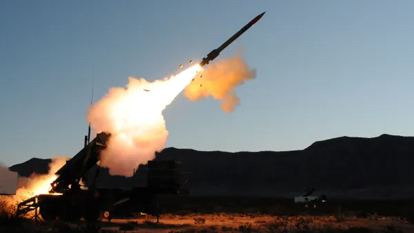 Smoke emitting from a missile shot out from a ground-based mobile launching station under a cloudless, evening sky.