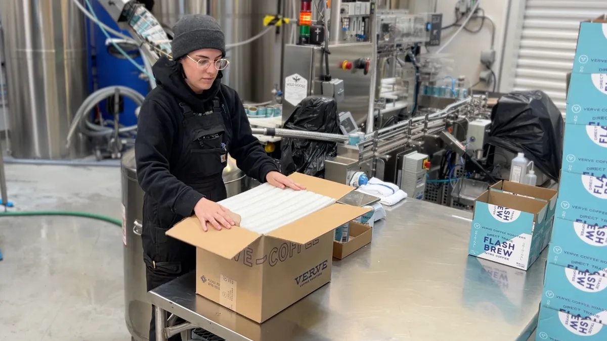 A person packing products into a box at a production facility.