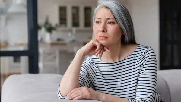 Older Asian woman looks sadly out of the window