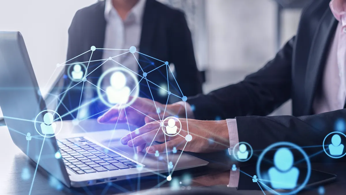 Two HR specialists in formal wear analyzing the recruitment market using laptop