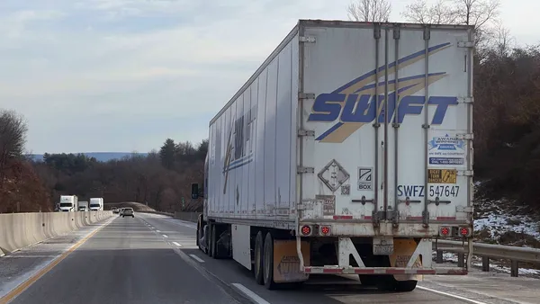 A Swift Transportation tractor-trailer proceeds along a highway.