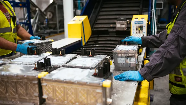hands of workers sort large batteries on a conveyor