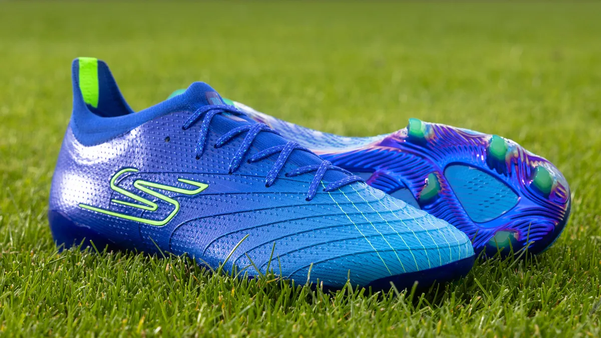 A pair of bright blue Skechers soccer cleats on a patch of grass.