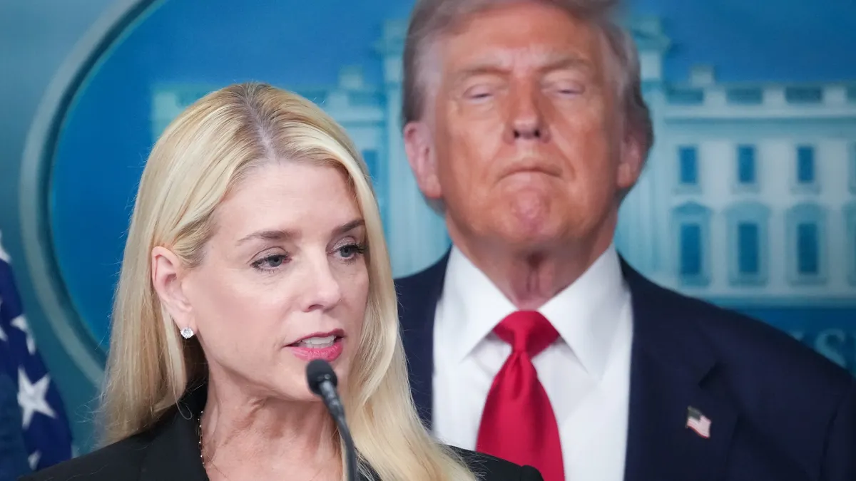 Attorney General Pam Bondi speaks into microphone with President Donald Trump behind her