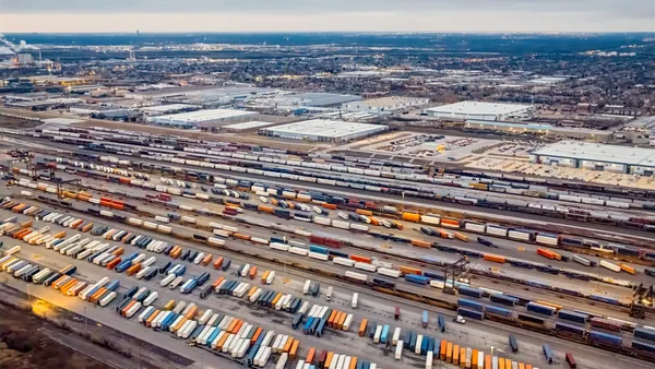 An aerial view shows a rail freight station with shipping containers and warehouses in Chicagoland.