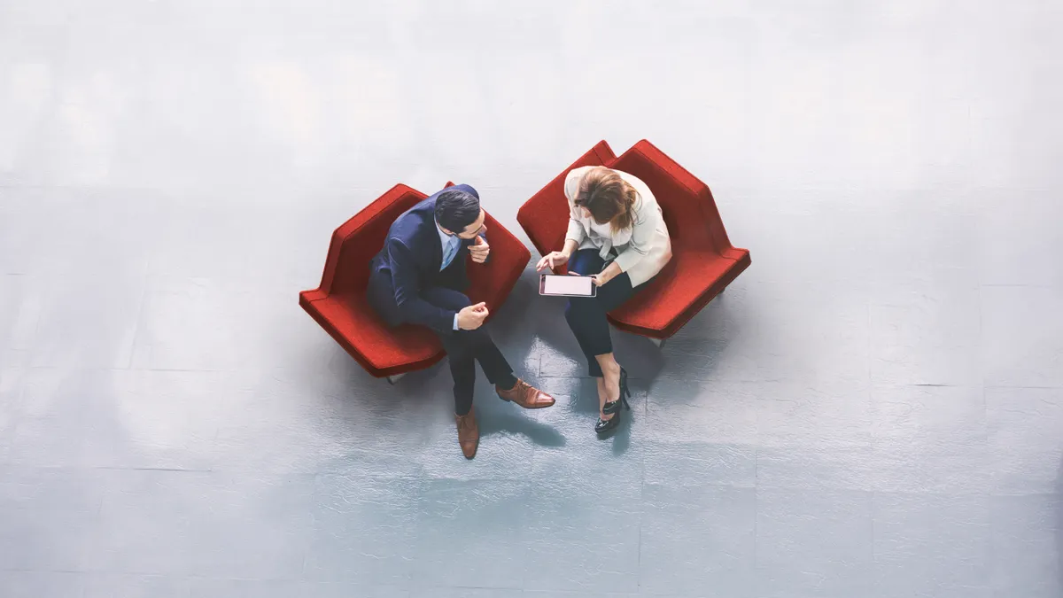 A high-angle view of a business perople sitting in the office building lobby and using a tablet computer