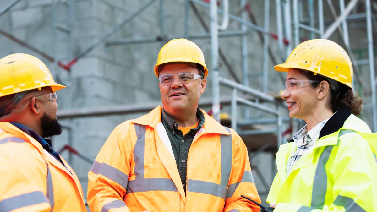 Three construction workers in protective gear conversing