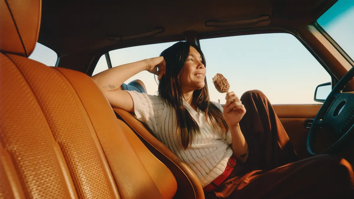 A person eats Häagen-Dazs in a car