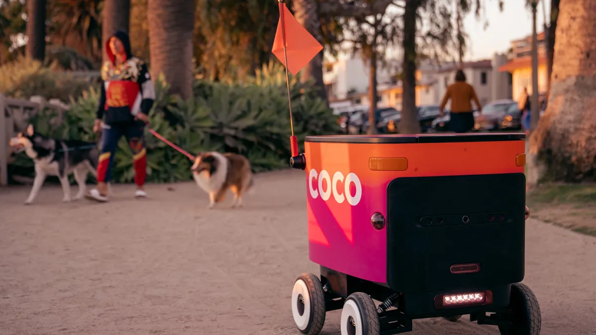 An image of a sidewalk robot with pink and orange painting.