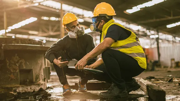 Two construction workers wear respirators on a jobsite.