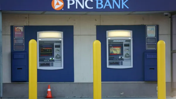 Two blue ATMs are housed within a modern facade featuring the PNC logo above and are accessible from the sidewalk. 