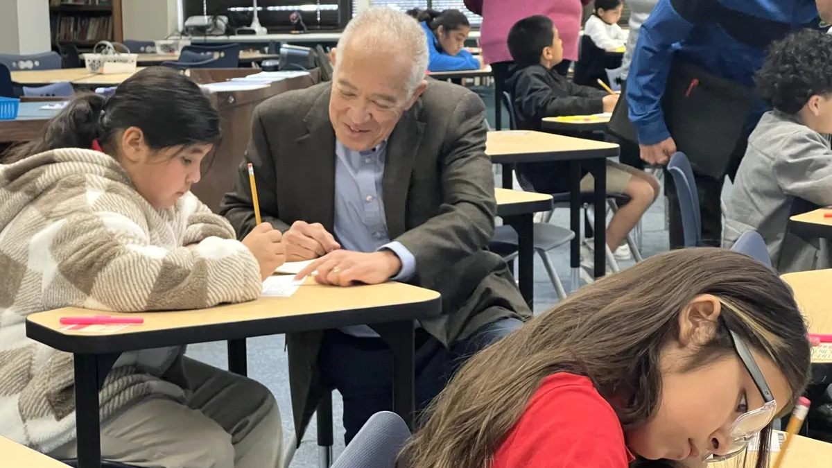 Houston Independent School District Superintendent Mike Miles kneels next to a student in a classroom