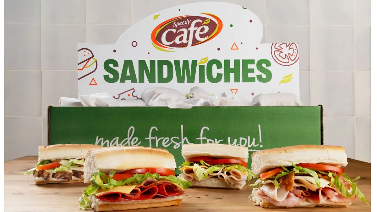 A photo of several sandwiches on a wooden table with a green and white box behind them that says Speedy Cafe Sandwiches.