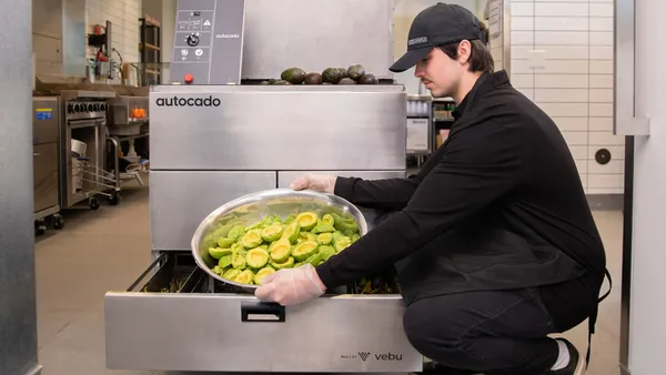 A worker takes a bowl of processed avocados from a prototype of Vebu's Autocado.