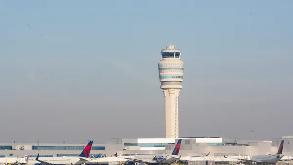 Planes go past the air traffic control tower as people travel through Hartsfield-Jackson Atlanta International Airport