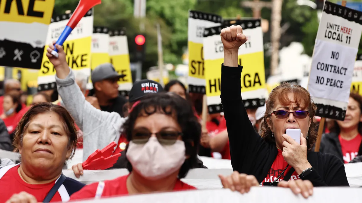 Workers hold picket signs saying 'ON STRIKE.'