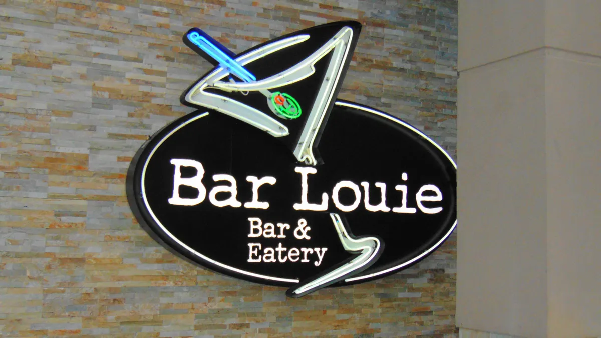 A brick wall with a black sign that says Bar Louie Bar & Eatery with a logo of a martini glass