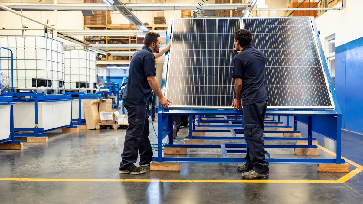 Green technology engineers building solar panels at a manufacturing plant.