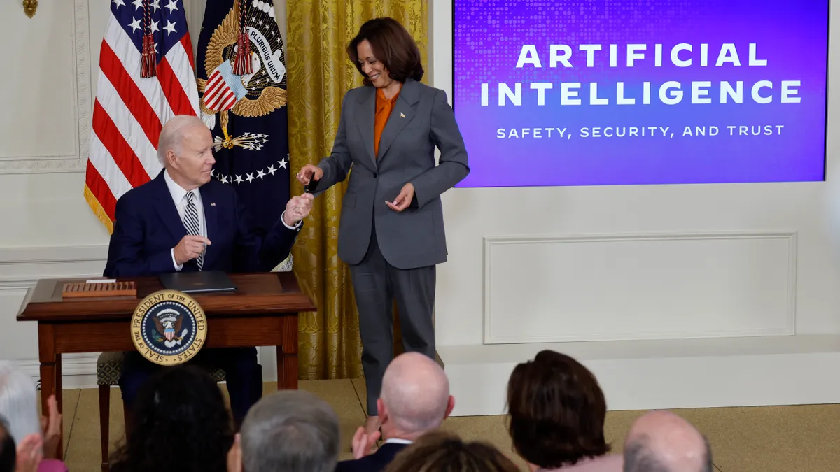 U.S. President Joe Biden hands Vice President Kamala Harris the pen he used to sign a new executive order regarding artificial intelligence during an event in the East Room of the White House on Octob