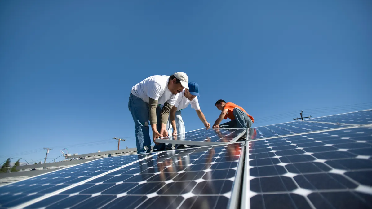 Workers installing solar panels on a house.