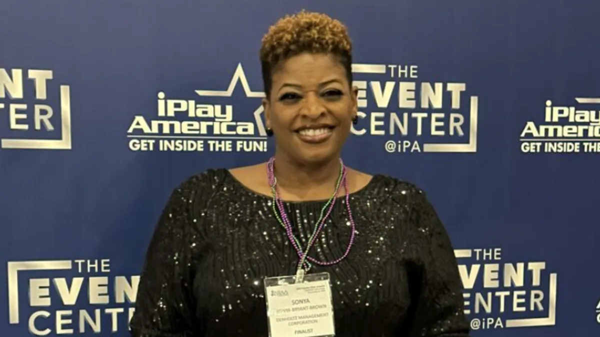 A woman dressed in formalwear stands with an award