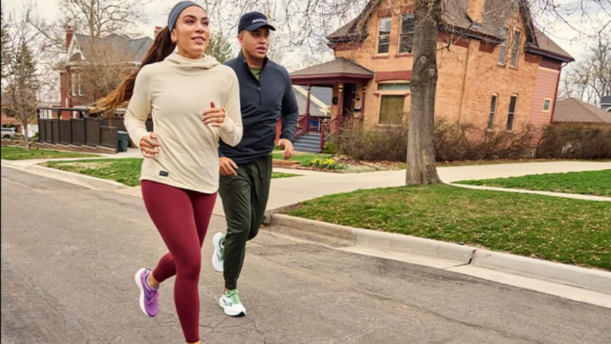 Two runners in athleticwear jog down a suburban street.