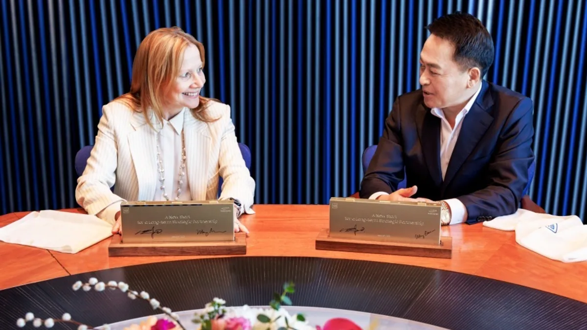 A man and a woman sign paperwork at a table