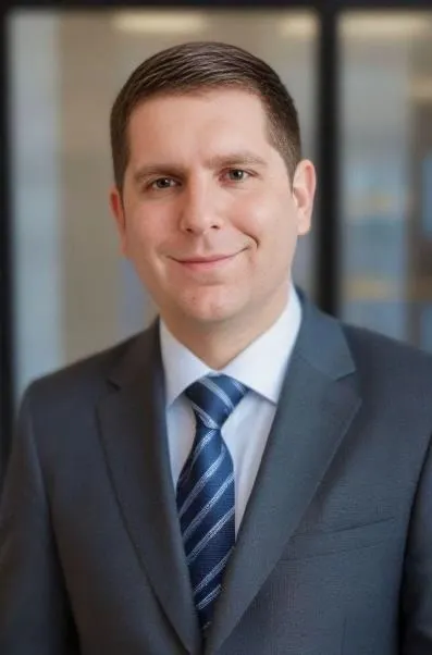 A person wearing a suit and tie smiles for the camera