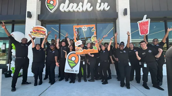 A photo of a number of people holding signs out in front of a store. A sign above the door says Dash In.