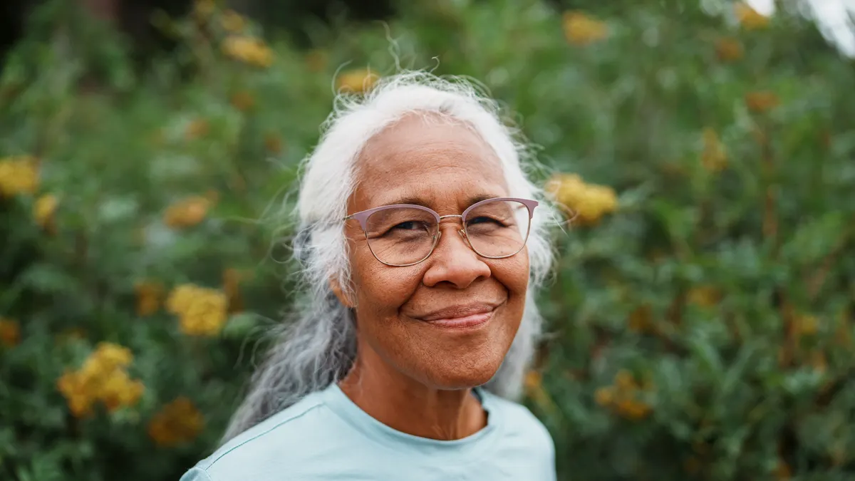 A white-haired person of Hawaiian and Chinese descent smiles at the camera.