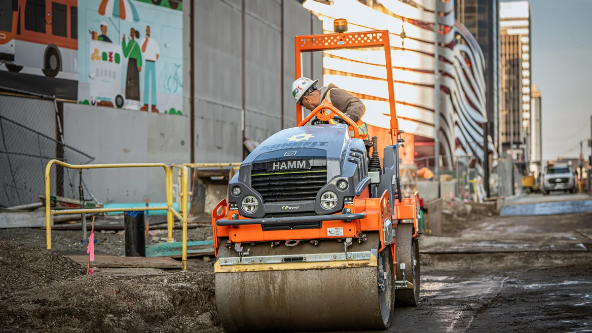 A heavy equipment operator drives a roller machine on a construction jobsite.