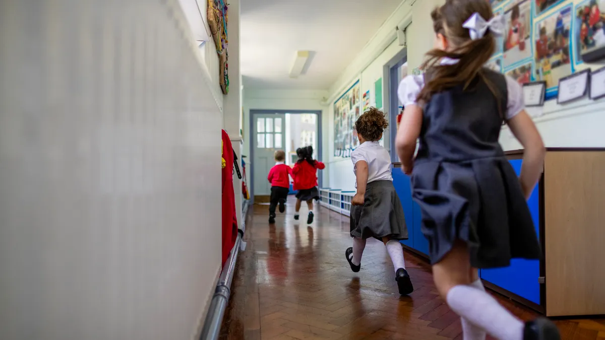 Students in uniform run down a school hallway