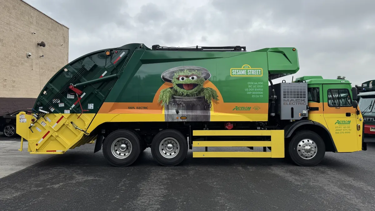 Side view of a garbage truck with a photo of Oscar the Grouch