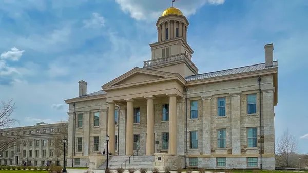 A domed stone building is seen against a blue sky with clouds.